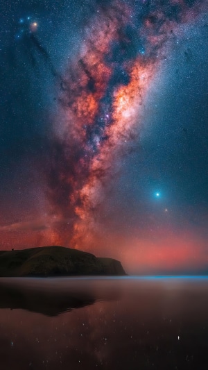 Milky Way galaxy over a reflective body of water and hills