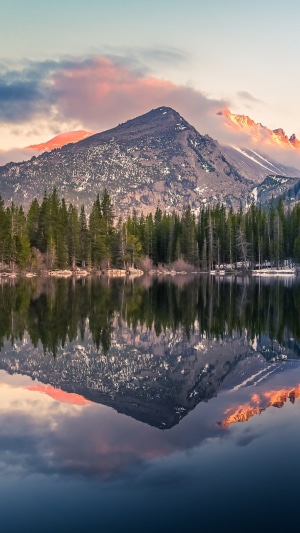 Mountain lake reflection with pine trees and clouds