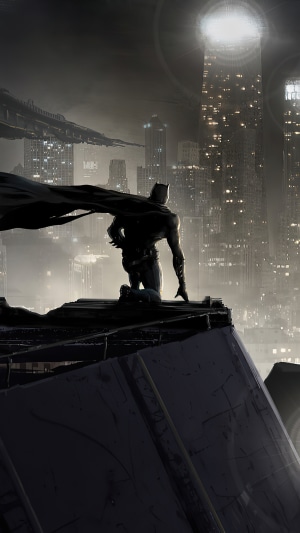 Batman kneeling on a rooftop overlooking a city
