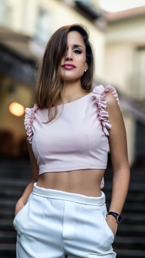 Woman in pink crop top and white pants