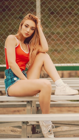 Model in red swimsuit and denim shorts wearing sneakers