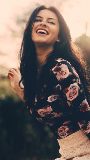 Young woman with dark hair smiling outdoors