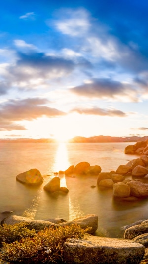 Sunset over a rocky lake shore 4K