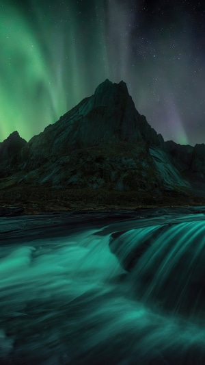 Aurora Borealis over mountains and waterfall