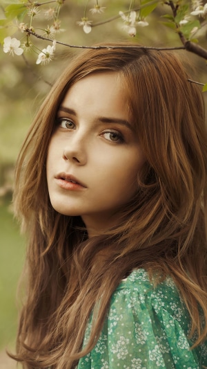 Young woman with long brown hair and green floral dress