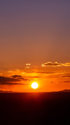 Sunset over a dark landscape with clouds