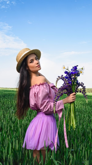 Girl in straw hat holding flowers in a field 4K