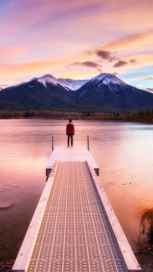 Man on pier at sunset with mountains