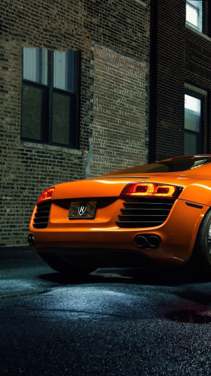 Orange Audi R8 parked by brick building