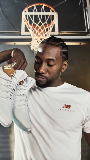 Kawhi Leonard holding New Balance basketball shoes