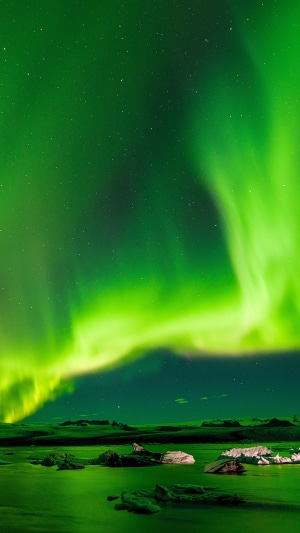 Northern Lights over a calm body of water with icebergs