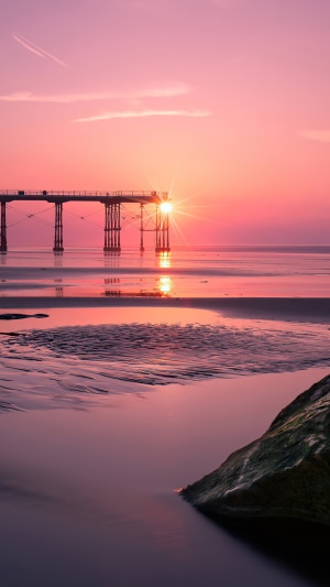 Sunset over a pier at a beach