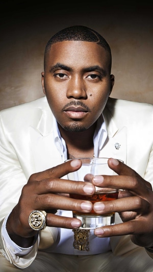 Nas in a white suit holding a drink