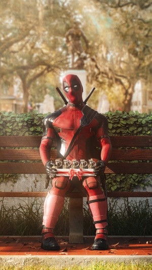 Deadpool holding a box of donuts in a park