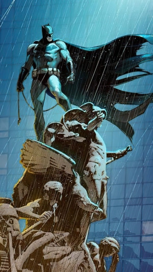 Batman standing on a statue in the rain