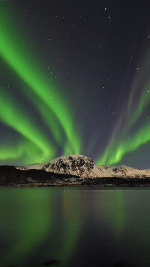 Aurora Borealis over snow-capped mountains and water