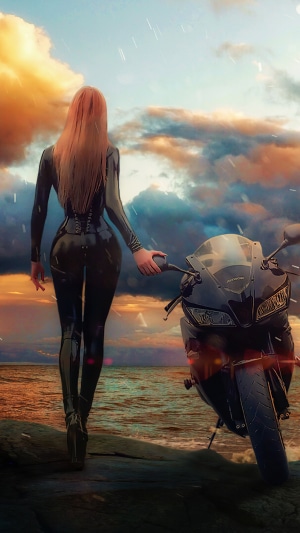 Woman in latex suit with motorcycle by the sea