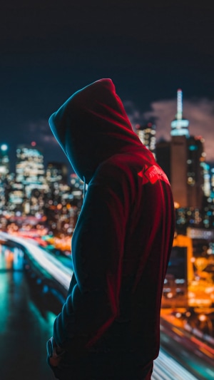 Person in hoodie against city skyline at night