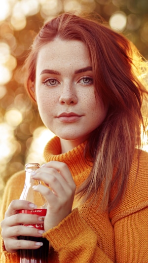 Young woman with freckles holding a Coca-Cola bottle
