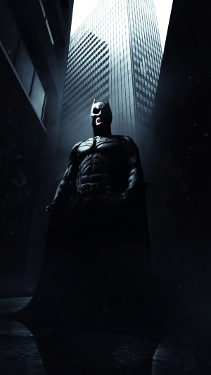Batman standing in a dark alley with a skyscraper behind him