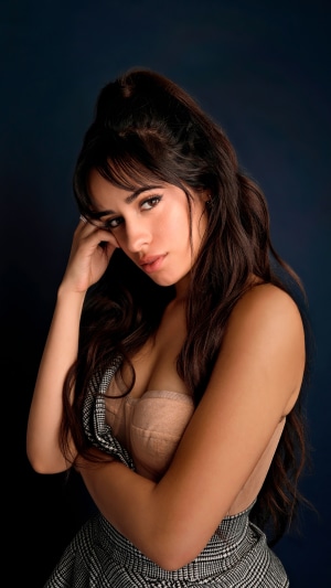 Camila Cabello posing against a dark blue background