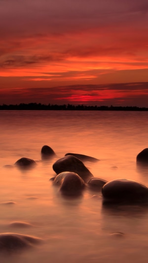 Sunset over water with rocks in foreground