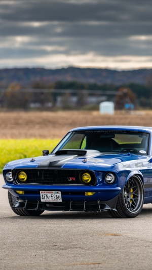 Blue Ford Mustang with racing stripes and yellow headlights