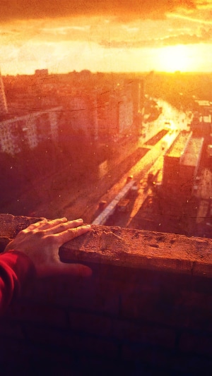 Hand on ledge overlooking city at sunset
