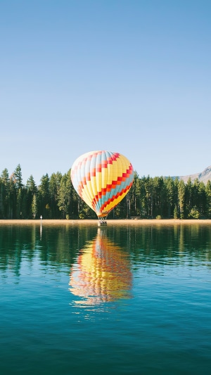 Hot air balloon over a lake with forest background