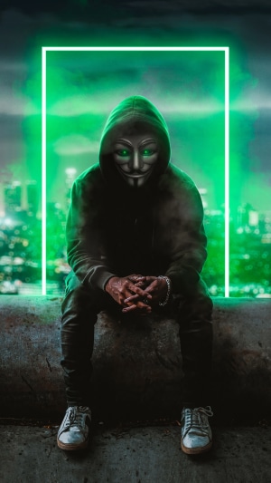 Anonymous figure in a hoodie and mask with green eyes