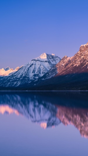 Snow-capped mountains reflected in a calm lake at sunrise