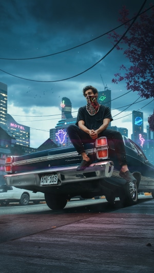 Man with mask sitting on a car in a city at night