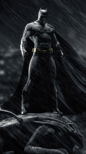 Batman standing on a gargoyle in the rain
