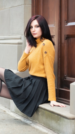 Woman in yellow sweater and black skirt sitting