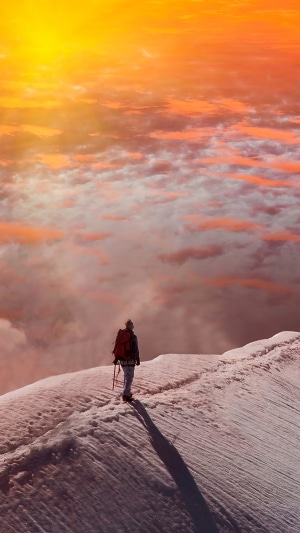 Hiker on snowy mountain ridge at sunset 4K