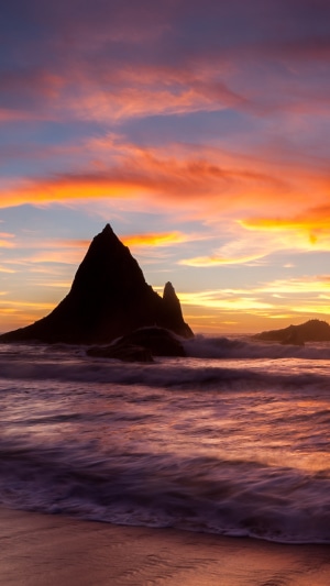 Sunset over a rocky beach with colorful clouds