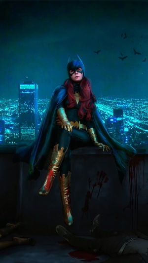 Batgirl sitting on a rooftop overlooking a city at night