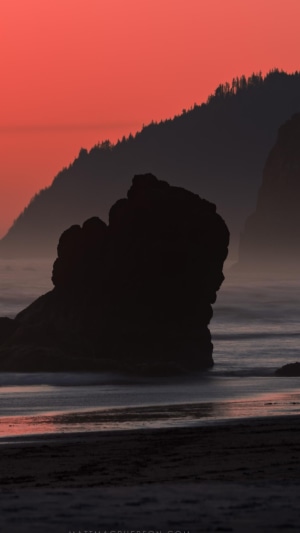 Silhouette of a rock formation on a beach at sunset
