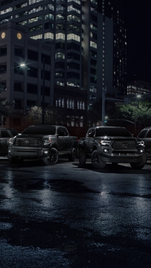 Toyota trucks parked on wet city street at night