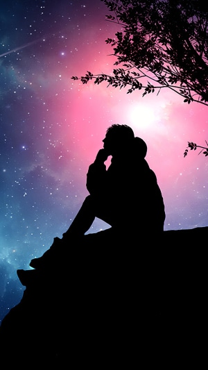 Silhouette of a person sitting on a rock under a starry sky