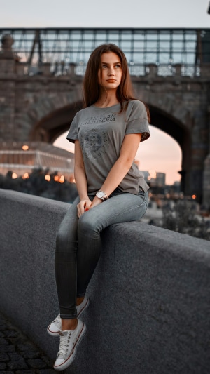 Girl in t-shirt and jeans sitting on a wall