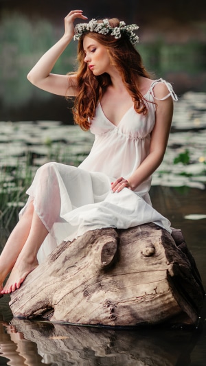 Woman with flower crown sitting on log in water