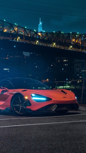 Orange McLaren 765LT parked near a bridge at night