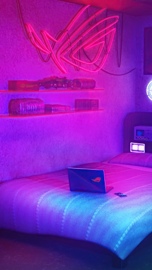 Republic of Gamers neon sign above shelves with laptop on bed