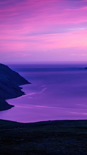 Purple sunset over a calm sea and rocky coast