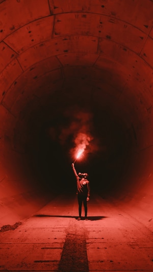 Person holding a red flare in a tunnel