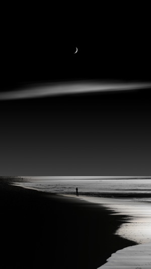 Person on beach with crescent moon and clouds