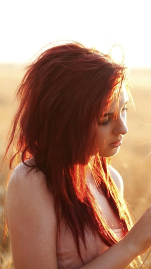 Redhead girl in a field at sunset