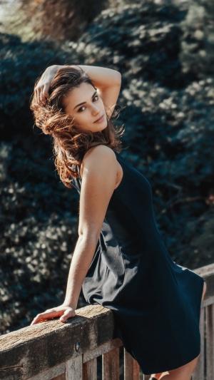Woman in black dress leaning on wooden railing