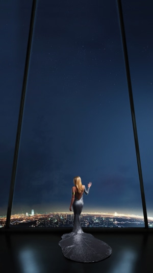 Woman in a silver dress overlooking a city at night